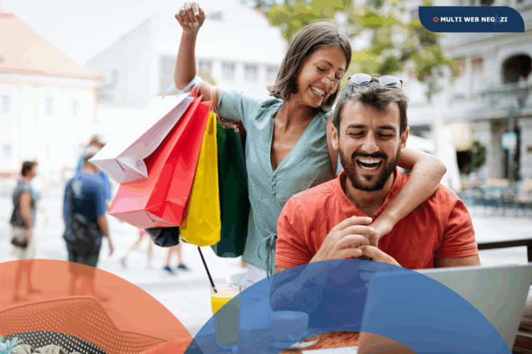 Coppia sorridente con sacchetti colorati dopo lo shopping, mentre guarda un laptop in un bar all’aperto.